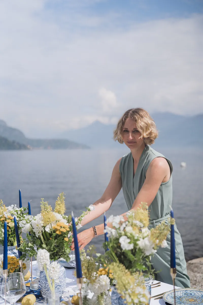 Amandine installe les compositions florales d'une table de mariage au bord d'un lac