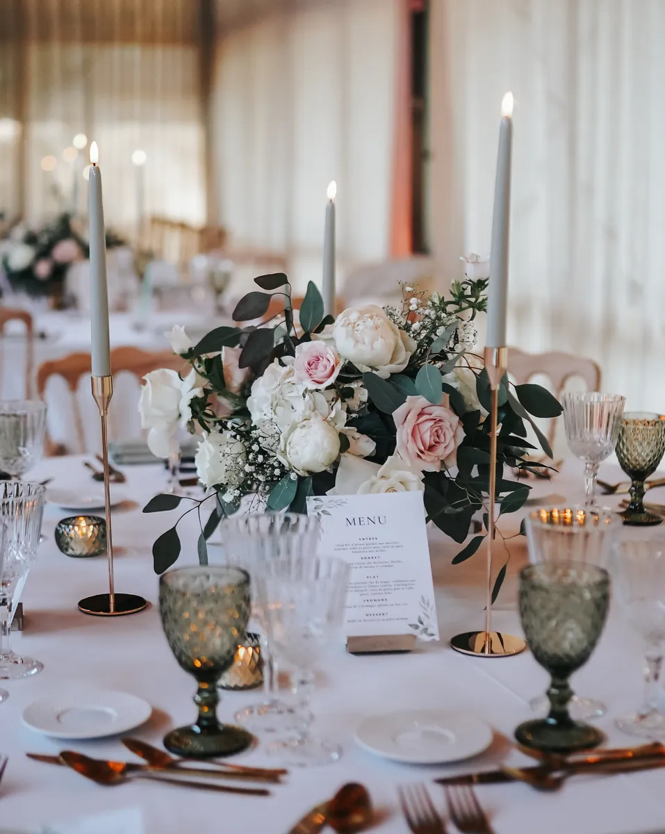 Table dressée avec bougeoirs, verres teintés et fleurs, matériel de décoration en location