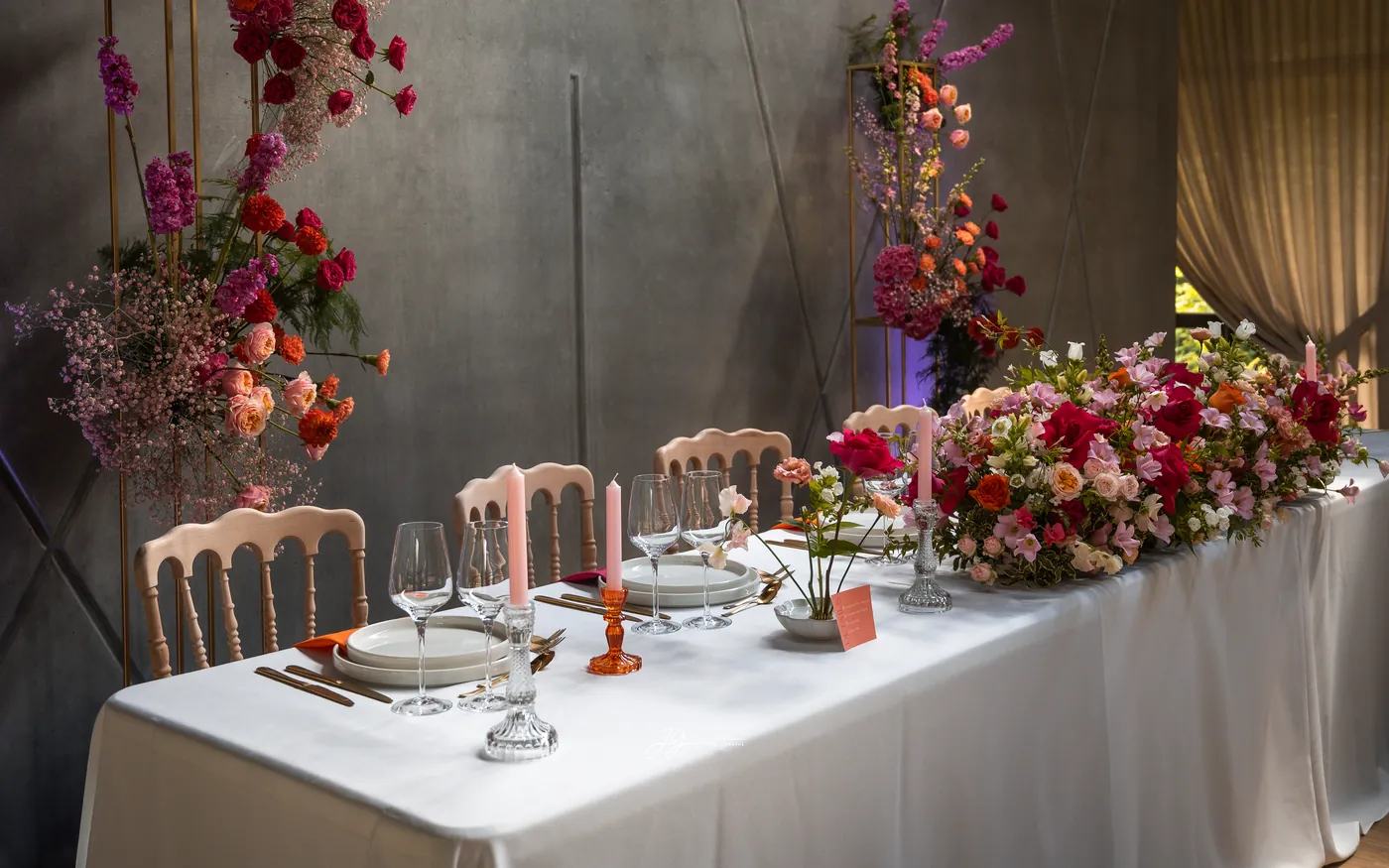 Scénographie d'une table de réception avec arche fleurie et chandelles