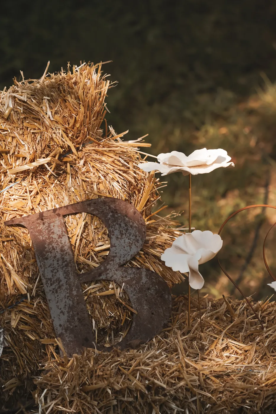 Initiale et fleurs en céramique créées par la mariée, posées sur une botte de paille