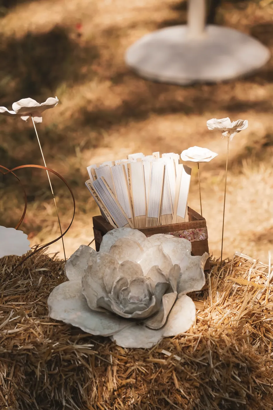 Livrets de cérémonie et fleur en céramique disposés sur la paille