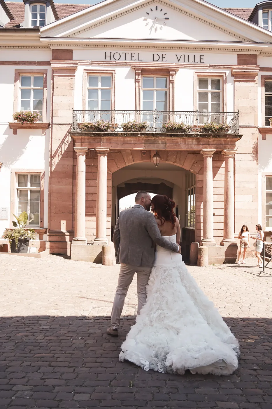 Les mariés s'embrassent devant l'hôtel de ville en grès rose