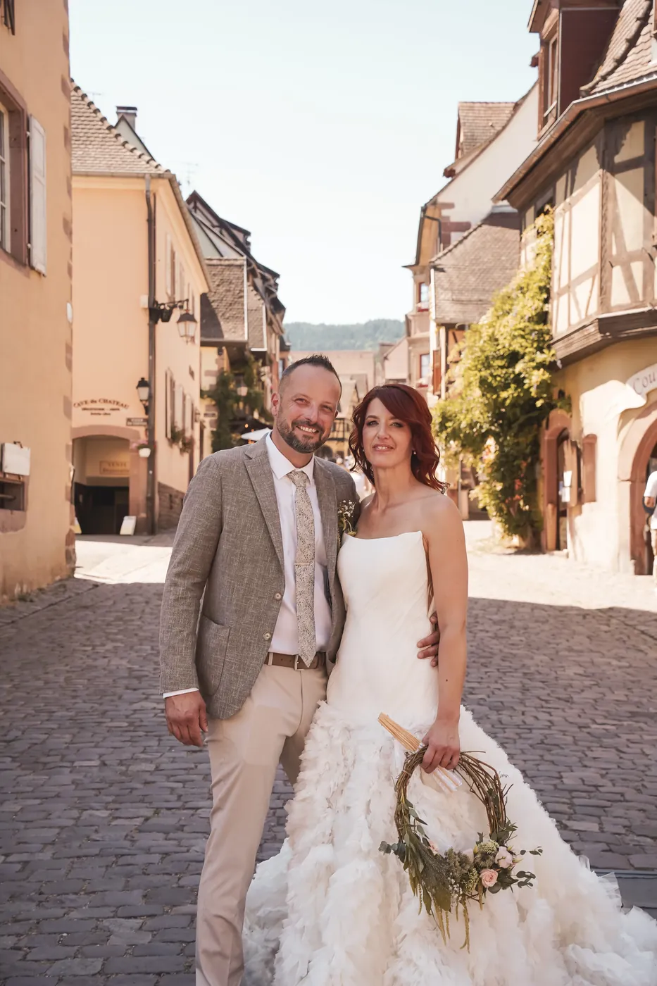 Charlotte et Bruno dans une ruelle de village alsacien bordée de maisons à colombages