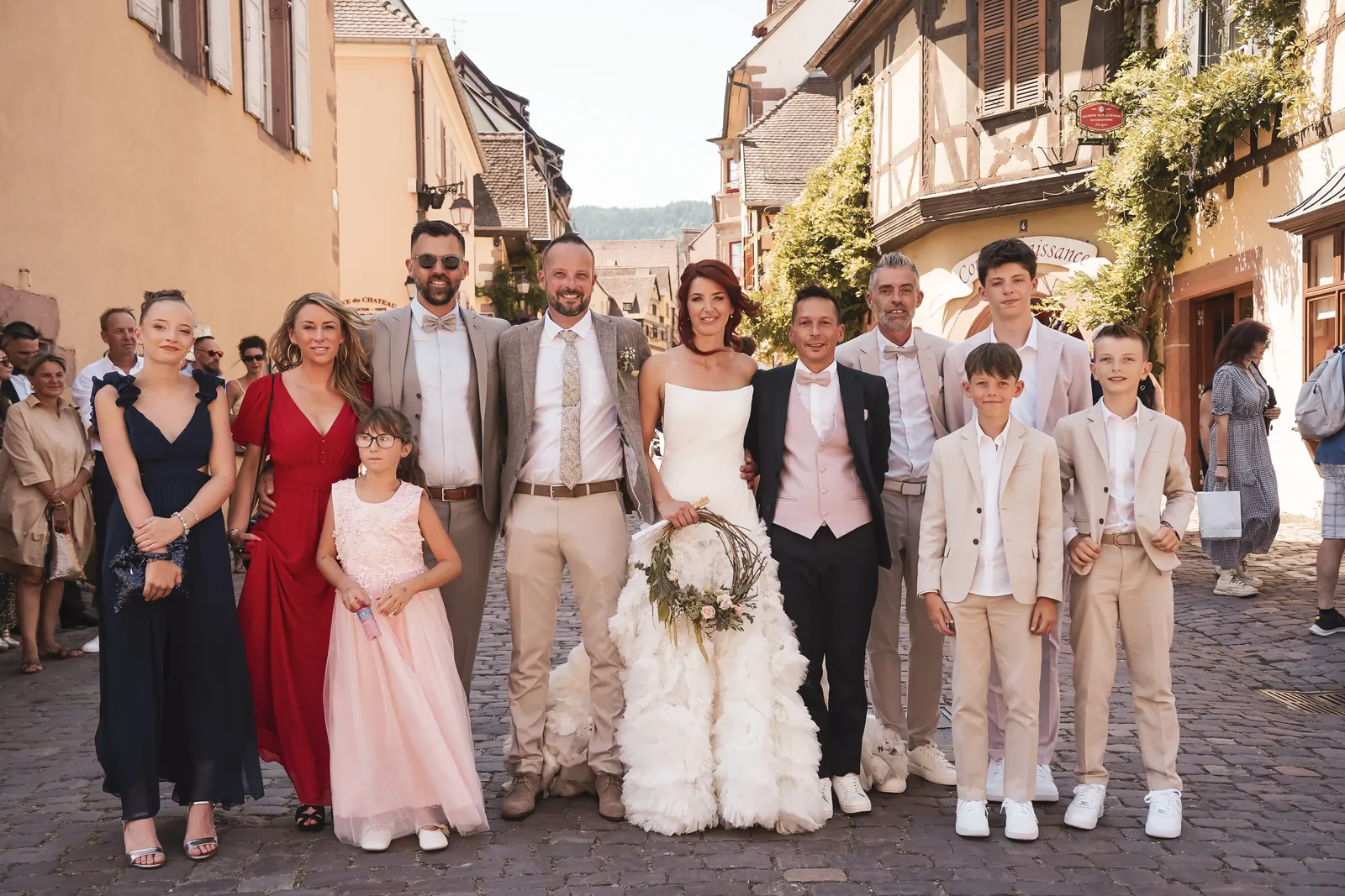 Photo de groupe des mariés et de leurs invités dans une rue du village alsacien